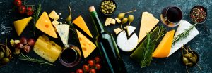 Wine, cheese and snacks on a black stone background. Assorted ch
